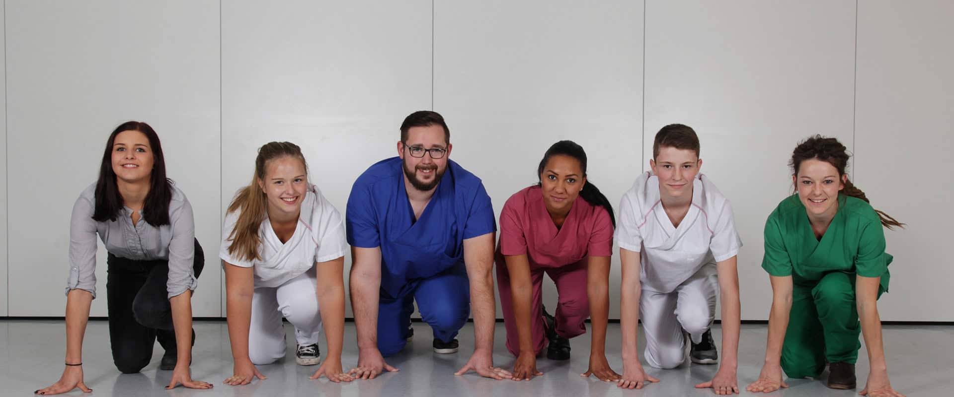 Kompetente pflegekräfte in sportlicher startposition bei einer schulungsübung im ausbildungszentrum.