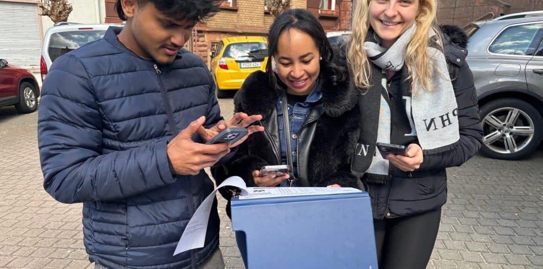 Studenten beim Austausch im öffentlichen Raum, alle schauen auf ihre Smartphones und tragen Winterkleidung.